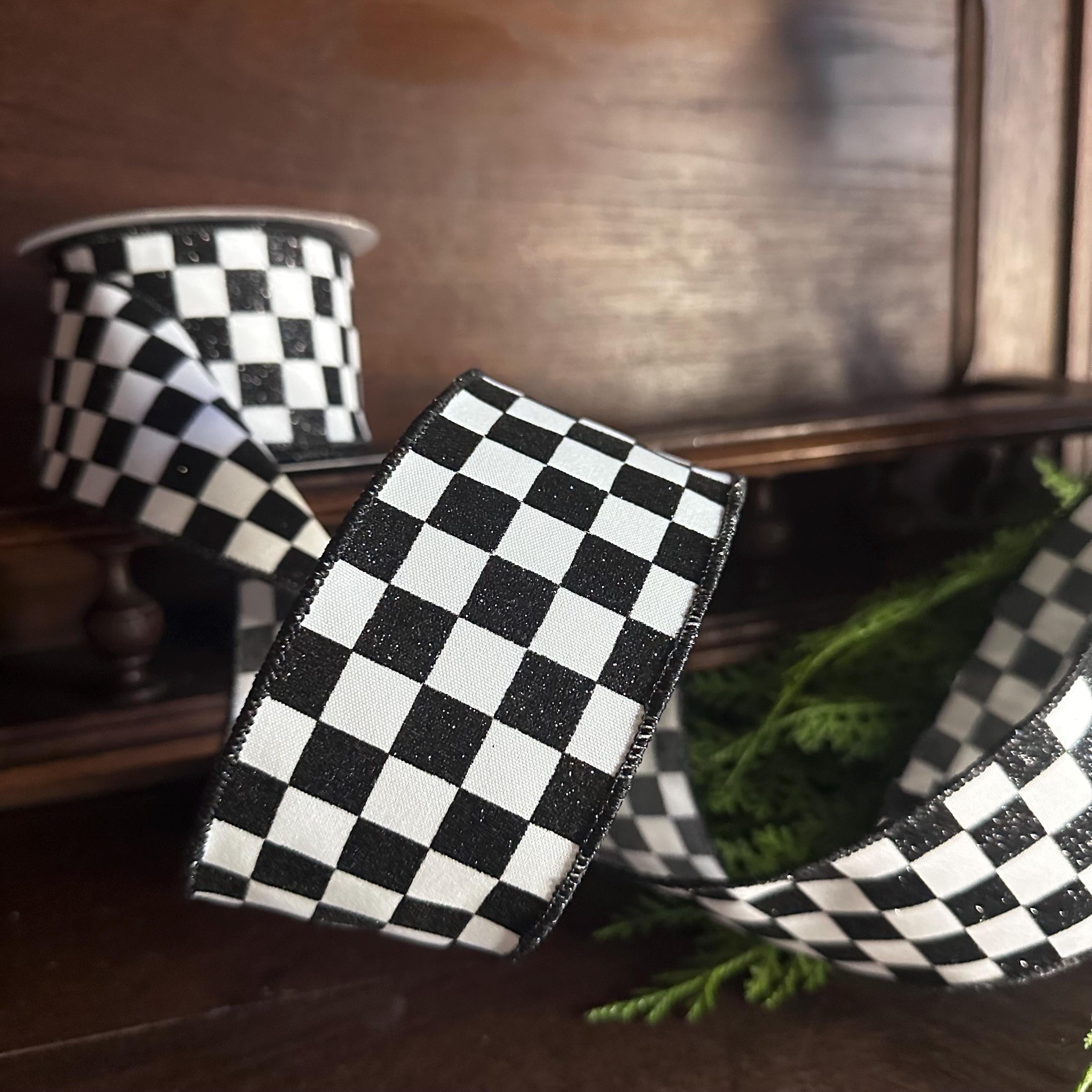 This is a black and white checkered wired ribbon, featuring a classic racing flag pattern. The ribbon appears to be made of a durable fabric material with wire edges that allow it to hold shape when bent or twisted. This type of ribbon is commonly used for race-themed party decorations, NASCAR event decor, automotive-themed wreaths, gift wrapping, and racing event celebrations. The checkered pattern is iconic in racing culture. It would also look cute with Valentines.